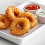 Golden onion rings fresh out of the air fryer with dipping sauces