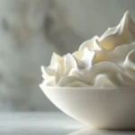 Freshly whipped crema Chantilly in a bowl on a marble surface.